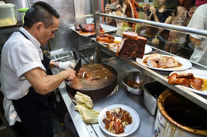 Primo street food al mondo ad aver ricevuto una stella Michelin. Nella foto vediamo lo Chef Chan Hon Meng mentre cucina in uno dei suoi due chioschi in Chinatown